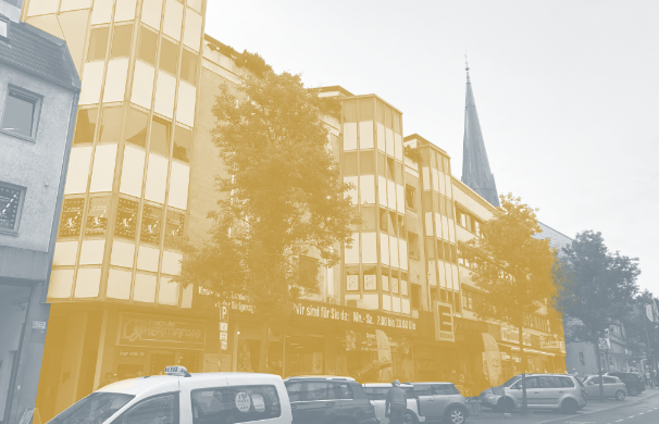 Das Bild zeigt eine gelb hervorgehobene Fassade eines Wohn- und Geschäftshauses der DWG. In der Umgebung sieht man den Stadtteil Kray in Essen.